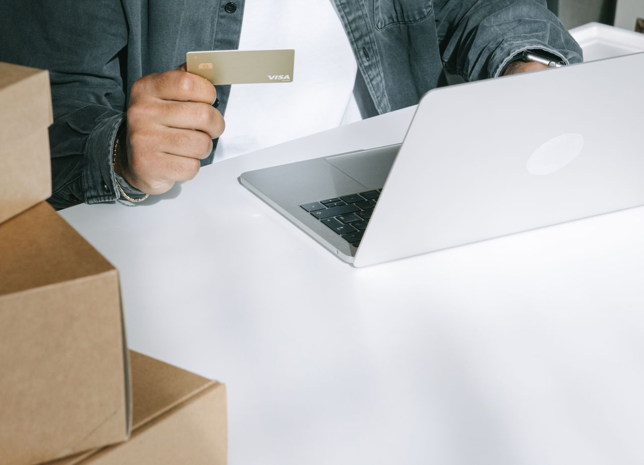 Home Person using a credit card for online shopping on a laptop surrounded by shipping boxes.